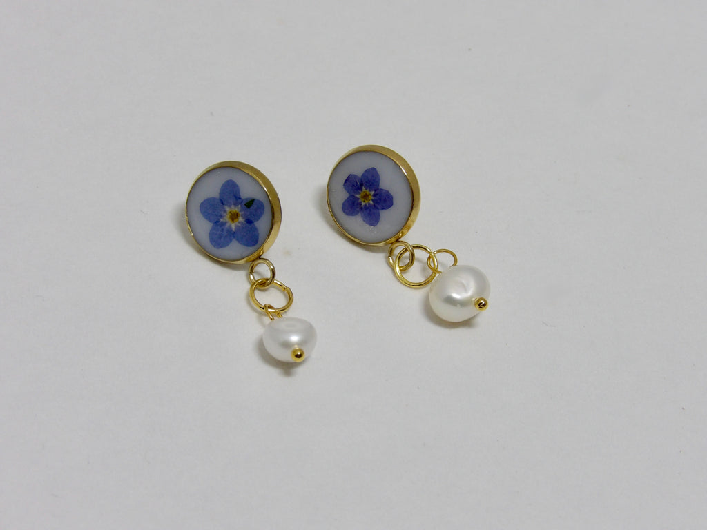 Pair of earrings with blue flower and pearl design on a white background